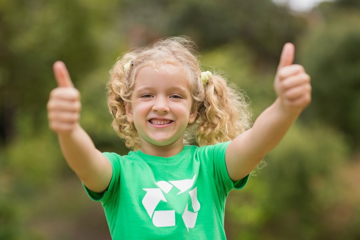 Happy child showing thumbs up in a green recycled shirt