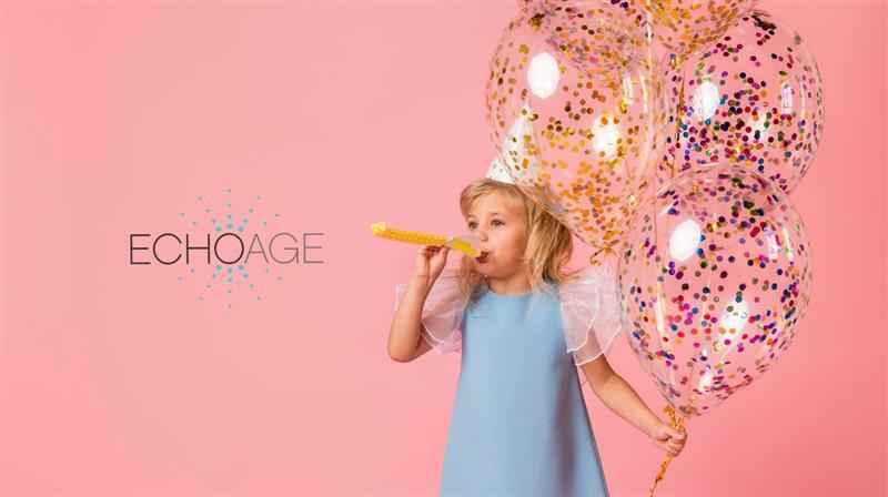 A young girl, against a pink background, in a baby blue princess dress with frilly sleeves, wearing a birthday pointed cone hat. She is blowing into a yellow party horn using her right hand, in her left hand are clear birthday party balloons, two with multicoloured glitter and one with yellow glitter. On the left hand side of the image is the ECHOage logo.