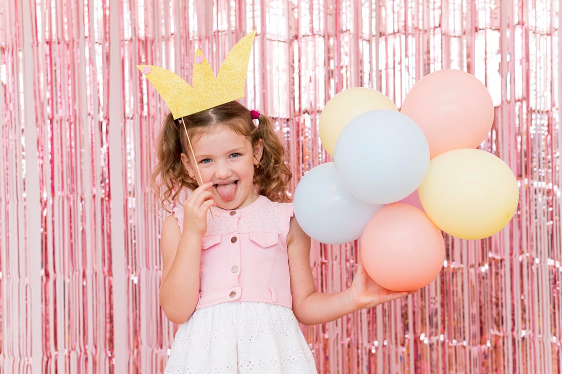 Child with a princess crown with balloons celebrating at a princess birthday party