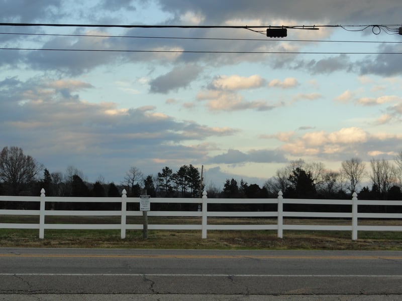 an empty field with a pole in the middle next to some high end housing