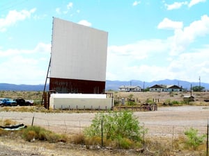 Closer view of screen. Large white plastic tanks in front of the screen are above-ground gasoline storage tanks for self-serve gas station occupying the corner of the property.