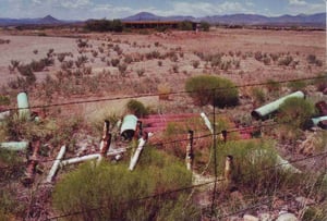 A pile of speaker poles has been dumped at the barbed wire fence