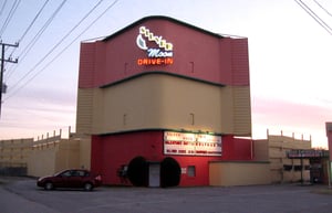 BACK OF SCREEN FROM STREET. THE ENTRANCE IS TO THE RIGHT. SHOT AT DUSK.