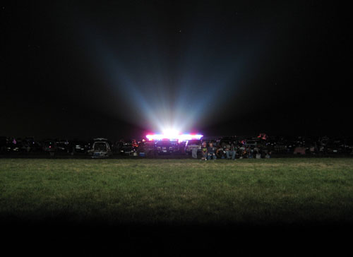 This is a long-exposure taken from below the screen towards the projector and concession building. The crowd is illuminated by the projector light.