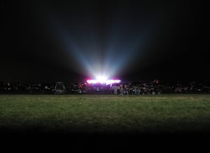 This is a long-exposure taken from below the screen towards the projector and concession building. The crowd is illuminated by the projector light.