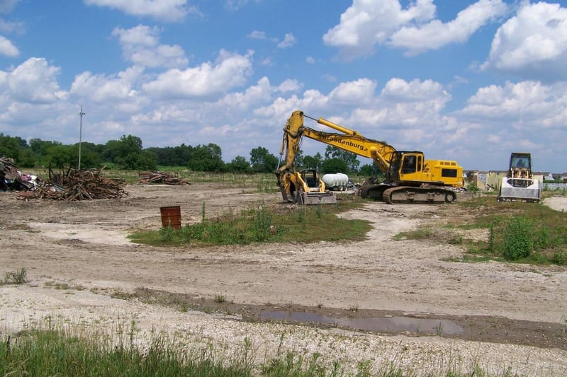 Field with piles of rubble.  Projection booth can be seen behind demolition machine.