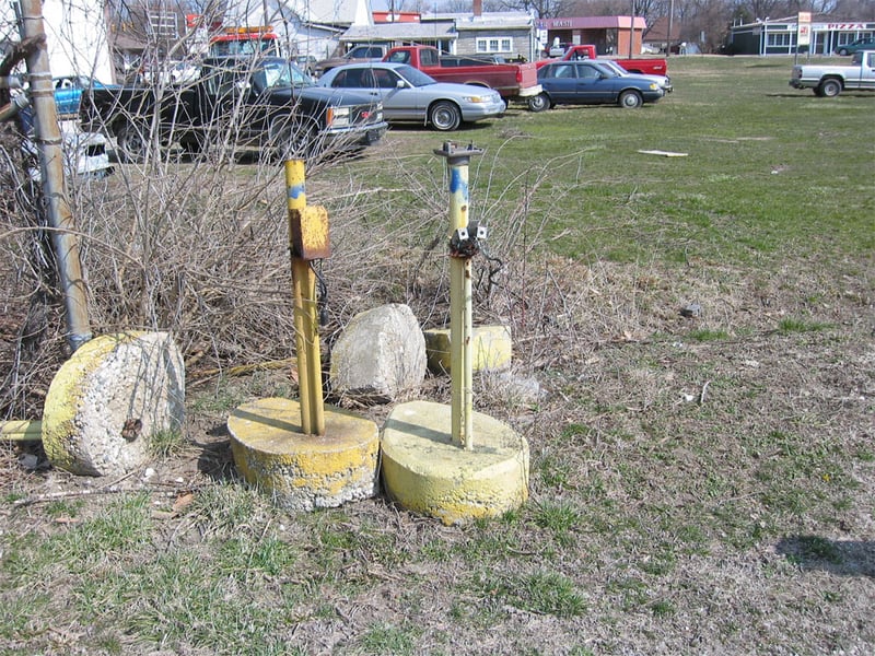 Some of the old speaker poles. The pole on the right was a speaker pole. Note the cut-off coiled black speaker cord, and the transformer on top. The speakers were stolen. The pole on the right is interesting. It has two 110v electric outlets hanging