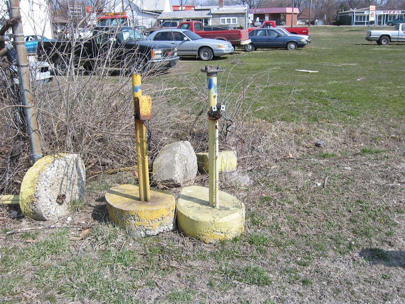 Some of the old speaker poles.  The pole on the right was a speaker pole.  Note the cut-off coiled black speaker cord, and the transformer on top.  The speakers were stolen.  The pole on the right is interesting.  It has two 110v electric outlets hanging