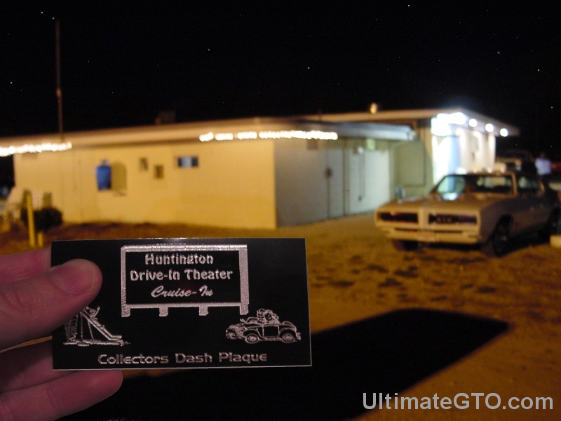 This is awesome.  I'm holding up an engraved metal Huntington Drive-In
Theater Collectors Dash Plaque.  The snack bar is in the background.  On
this evening we were especially hungry, and yes, we can recommend the
delicious pizza and the popcorn.  Ever