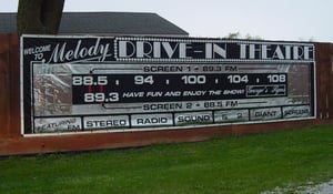 A handsome silver and black banner sign at the entrance. It tells you which FM stations to tune in for the stereo movie sound.