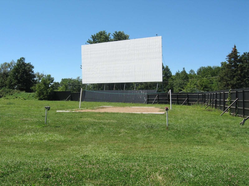 SCREEN AND VOLLEYBALL COURT. IT BEING AUGUST, PEOPLE WERE THROWING FOOTBALL ON NICE, LARGE LAWN AREA IN FRONT OF SCREEN. SMOOTH GRASSY HUMPS, NO DUST OR GRAVEL.