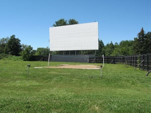 SCREEN AND VOLLEYBALL COURT. IT BEING AUGUST, PEOPLE WERE THROWING FOOTBALL ON NICE, LARGE LAWN AREA IN FRONT OF SCREEN. SMOOTH GRASSY HUMPS, NO DUST OR GRAVEL.