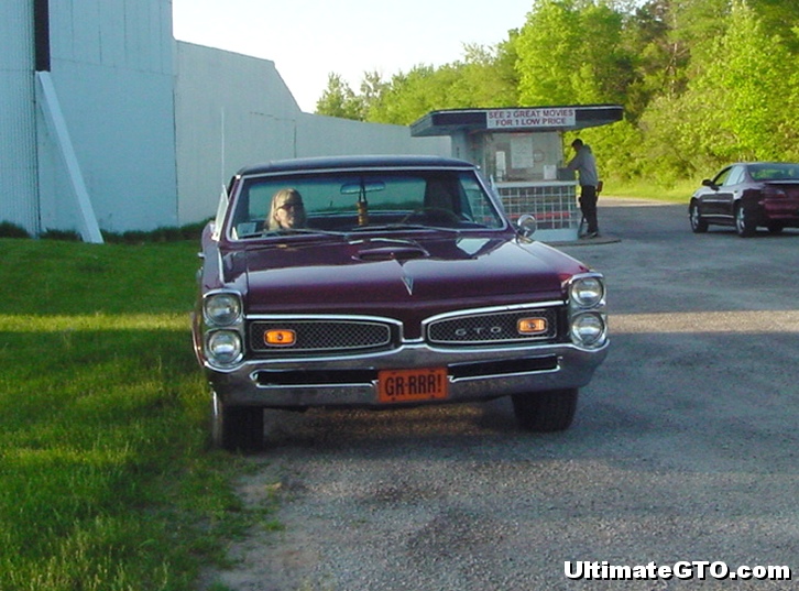 A 1967 GTO parked on the entrance driveway on a Saturday night. Behind it is the ticket window.
