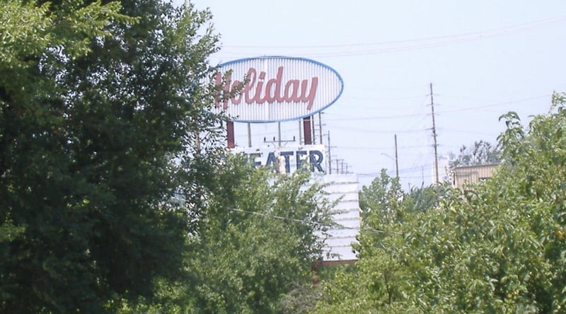 A closer view of the Holiday's sign, almost covered by trees.