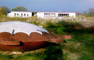 This is a circa-'95 photo (with a little digital damage; sorry) of the projection/concession building and part of the playground at the old 63 Drive-In.  I believe this merry-go-round was retained, or at least replaced by an identical one.