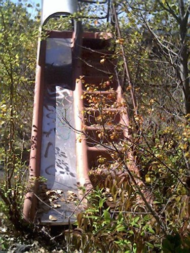 A slide at the playground which is fenced in with all the other equiptment.