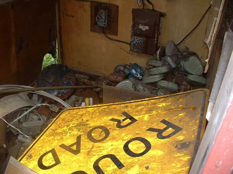 Inside shot of Small electrical shed. Lots of speakers, looks like film reels(?), and a rough road sign? - Whats that about?