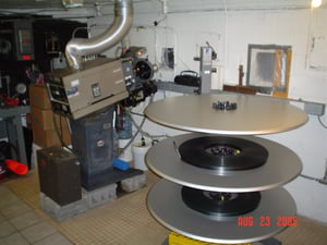 Projection room...They used a mutt until 2002. They took one projector out in 2002 and put in a platter. Notice the rotating lens turret on the projector. "Madagascar" and "Sky High" are the features on the platter.