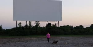 Lynn Carpenter walking dogs (Indy - lab and Lilly - Yorkie) in front Screen two in Pit Area.