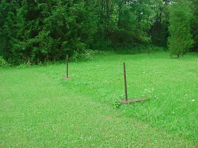 The undersized speaker poles and standards remain in a well-manicured lawn.