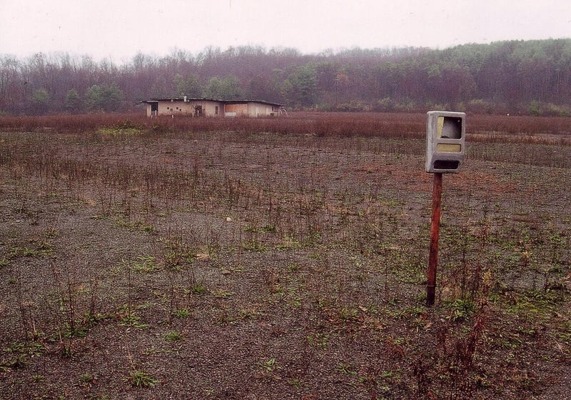 Picture of field with projection/concession building and lonely light fixture taken on a foggy day