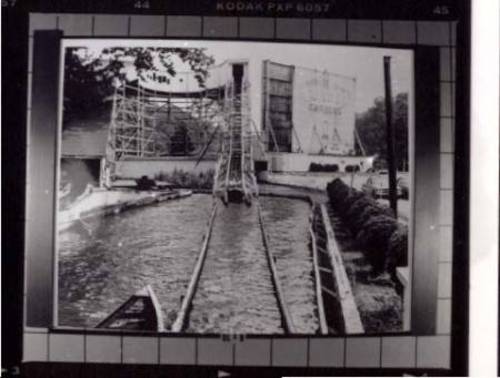 He is a negative of the back of the drive in. in the background. with the rollercoaster on the left.