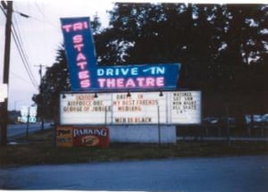 Marquee of Tri-State Drive-In lit at night with neon.