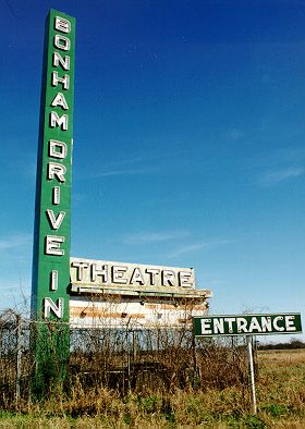 My friend took this photo of the Bonham Drive-in marquee and entrance sign back in 1999. The ticket booth is also standing but is so overgrown that he couldn't get a decent photo of it. Anybody have an old photo of this drive-in they could post?