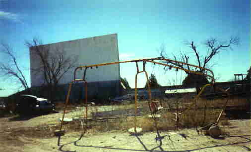 Photo showing the old rusted swingset infront of the screen.