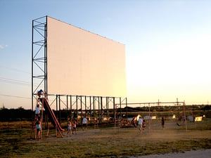 Kids playing on the playground on front of the screen.