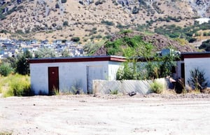 Closer shot of the projection area of the building, projection area is behind fence the holes are covered with brush.