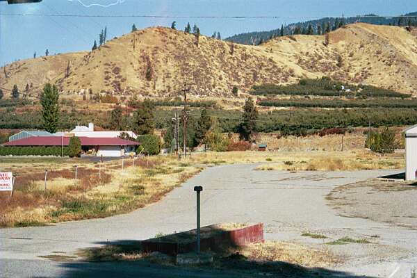 Entrance road and base of marquee for this theater. In the foreground and along the left side are speaker posts defining the edge of the property