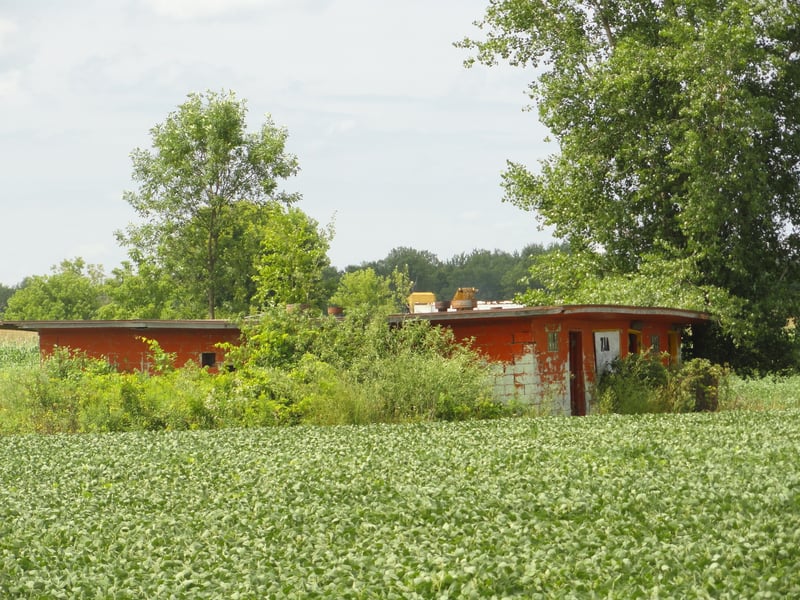 Former projectionconcession building still standing-pile of poles in the middle of the field