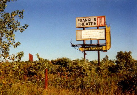 pic of the marquee and of the screen in the distance. the marquee no longer stands, and the screen supports are all that remain of the screen.