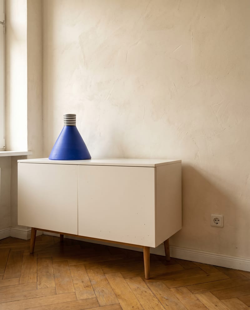 Sideboard Deko Idee im Dopamin Stil: cremeweißes Sideboard mit einer blauen Kegelvase als einzigem Farbträger