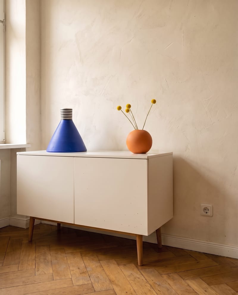 Sideboard Deko Idee im Dopamin Stil: blaue Kegelvase und orange Kugelvase mit Craspedia als Komplementärpaar