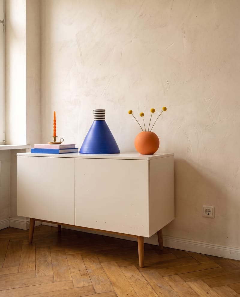 Sideboard Deko Idee im Dopamin Stil: Bücherstapel in Blau und Rosa mit Messing Kerzenständer und oranger Kerze