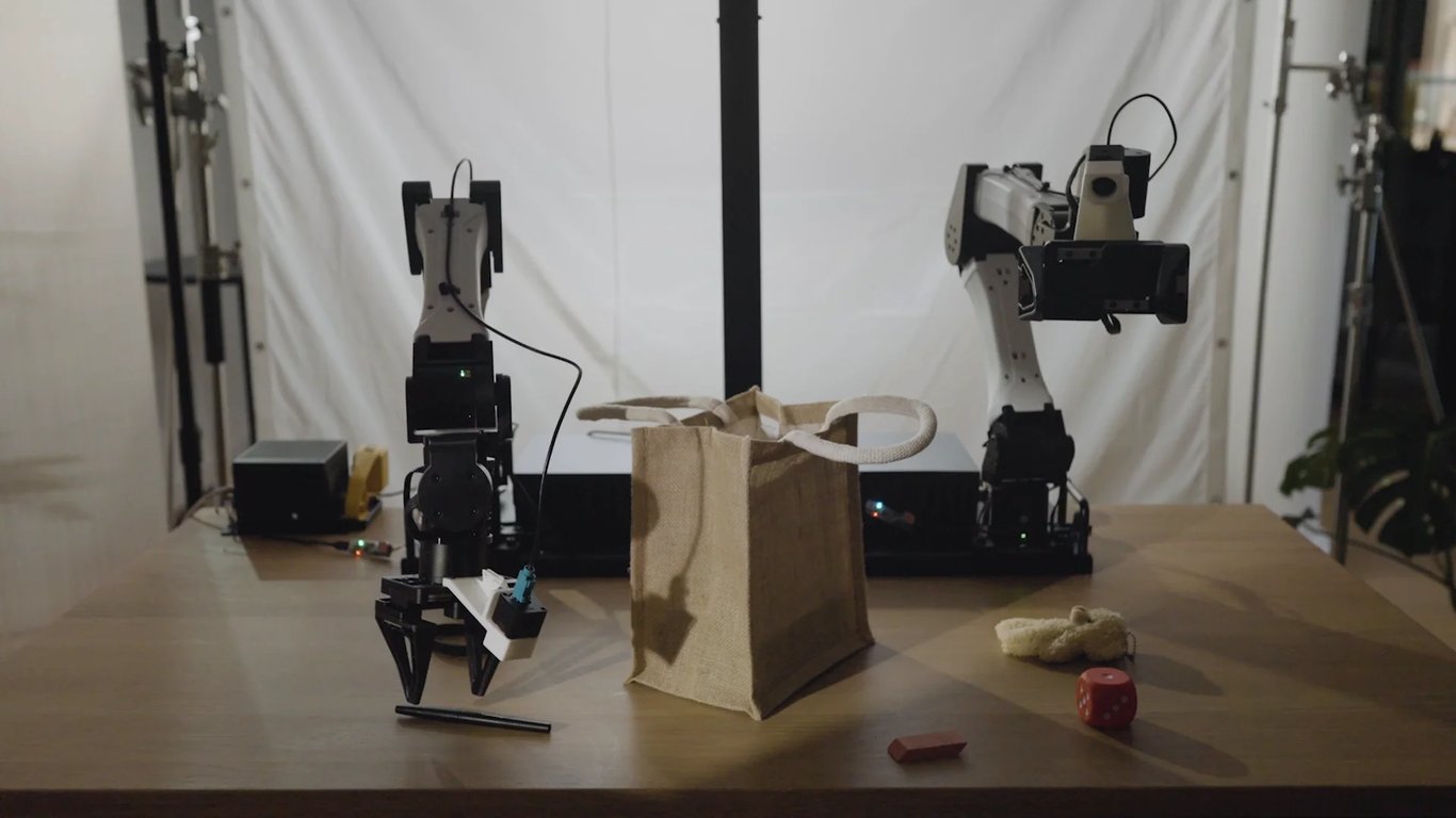 Bimanual robot rig with cameras and a canvas bag on a table