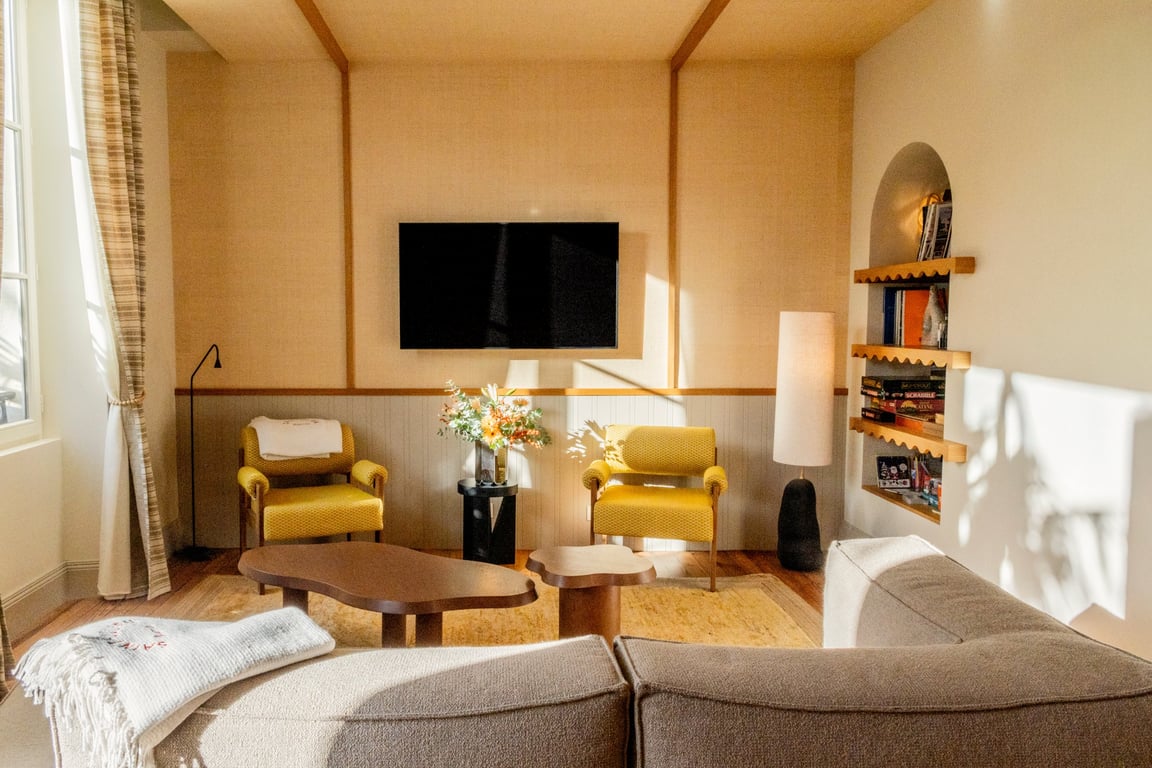 Suite avec salon spacieux, fauteuils jaunes, mobilier en bois et écran de télévision mural