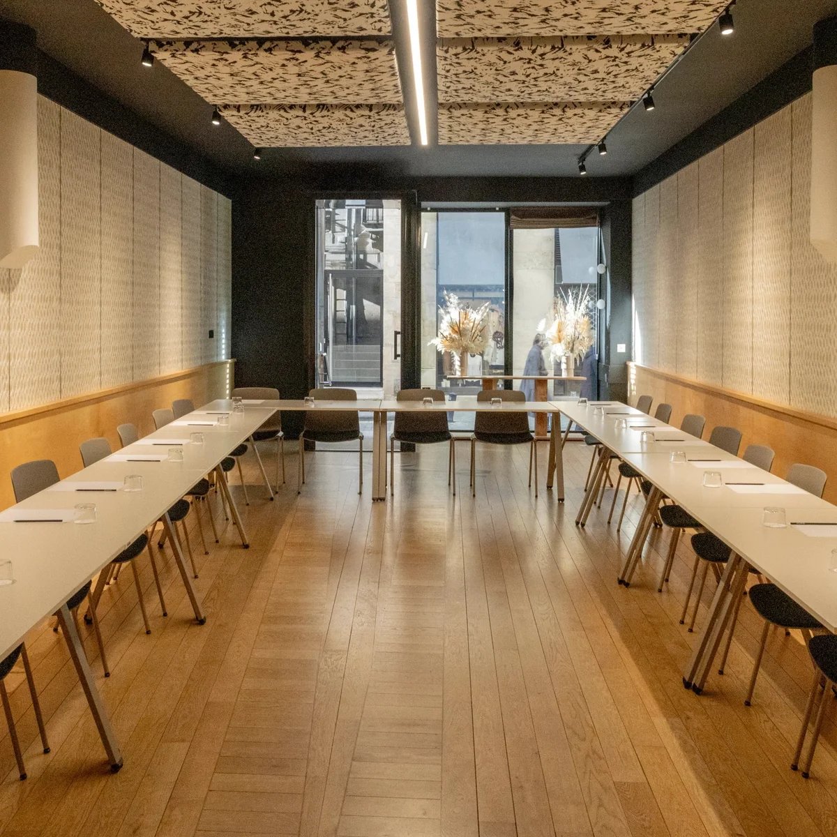 Modern meeting room featuring white tables, grey chairs and floor-to-ceiling windows overlooking the sea.