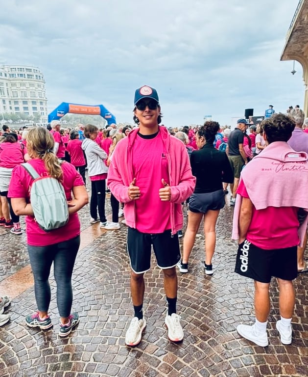 Participant à un événement sportif en rose dans une place publique avec foule et bâtiments en arrière-plan.