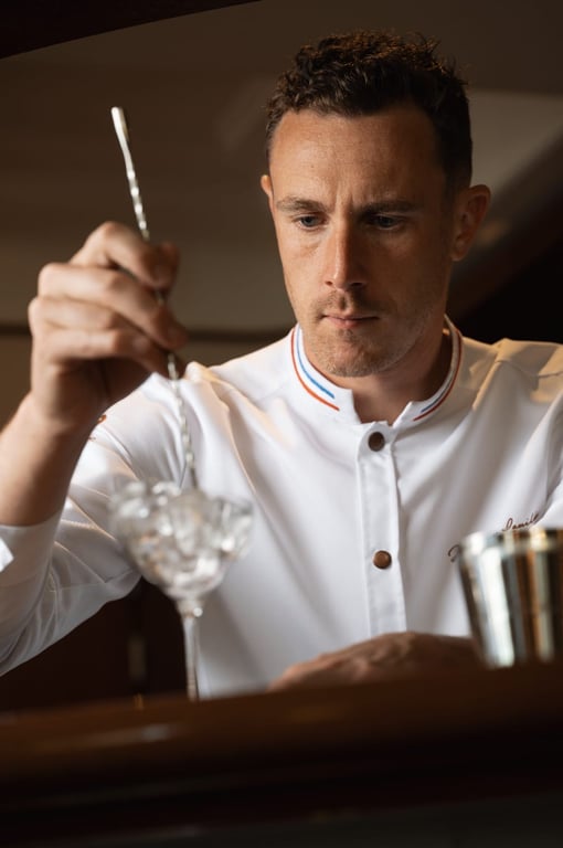 Barman en veste blanche préparant un cocktail au comptoir