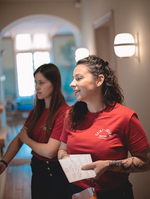 Two team members in red T-shirts, one holding her notes
