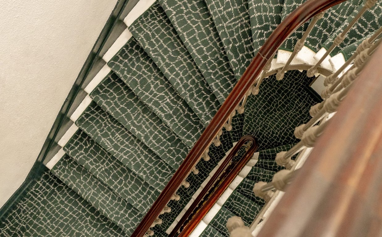 Escalier en colimaçon de la maison Gambetta à Bordeaux, moquette verte et rampe en bois