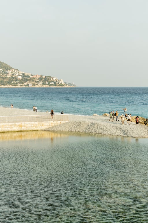 Mediterranean beach with swimming, stone waterfront promenade and clifftop coastal village