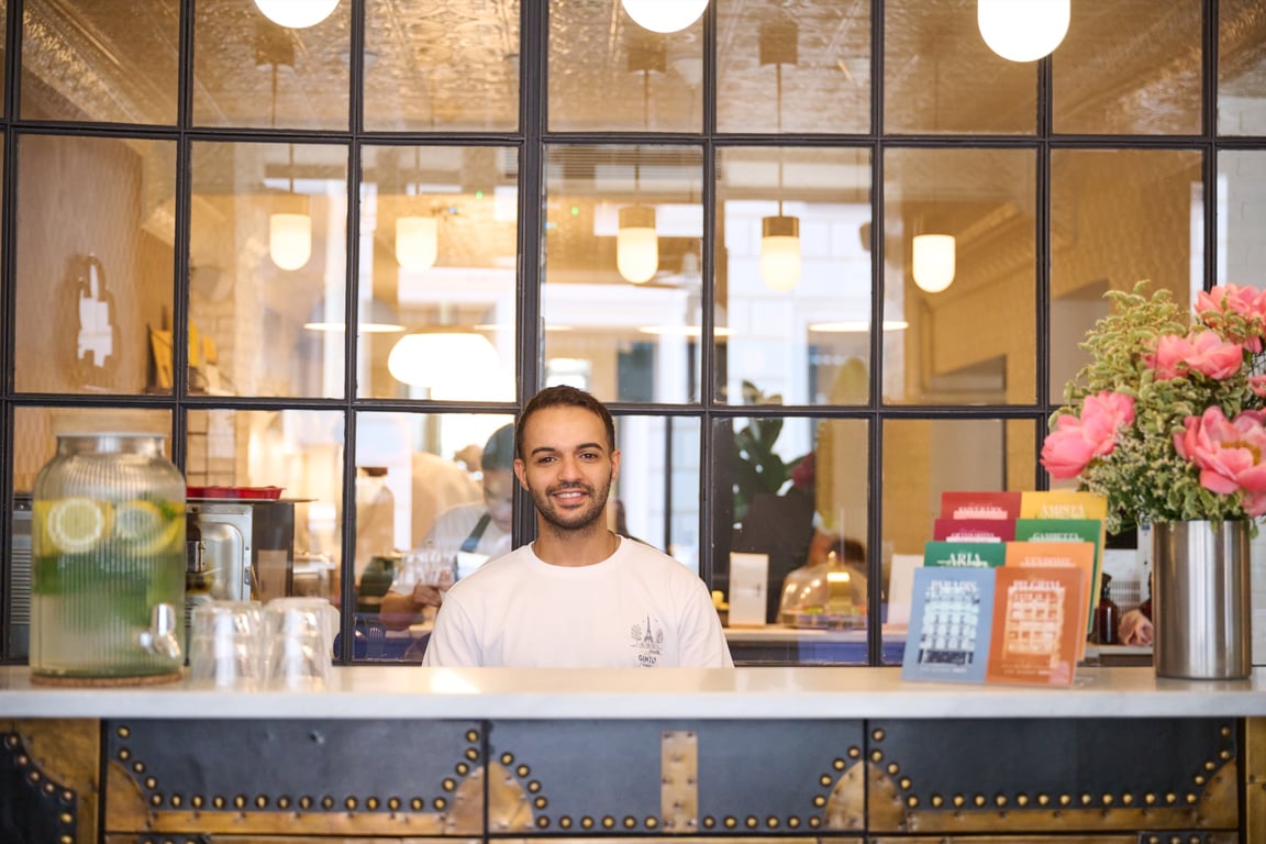 Smiling team member behind the counter of a Ginto house, in front of a glass partition