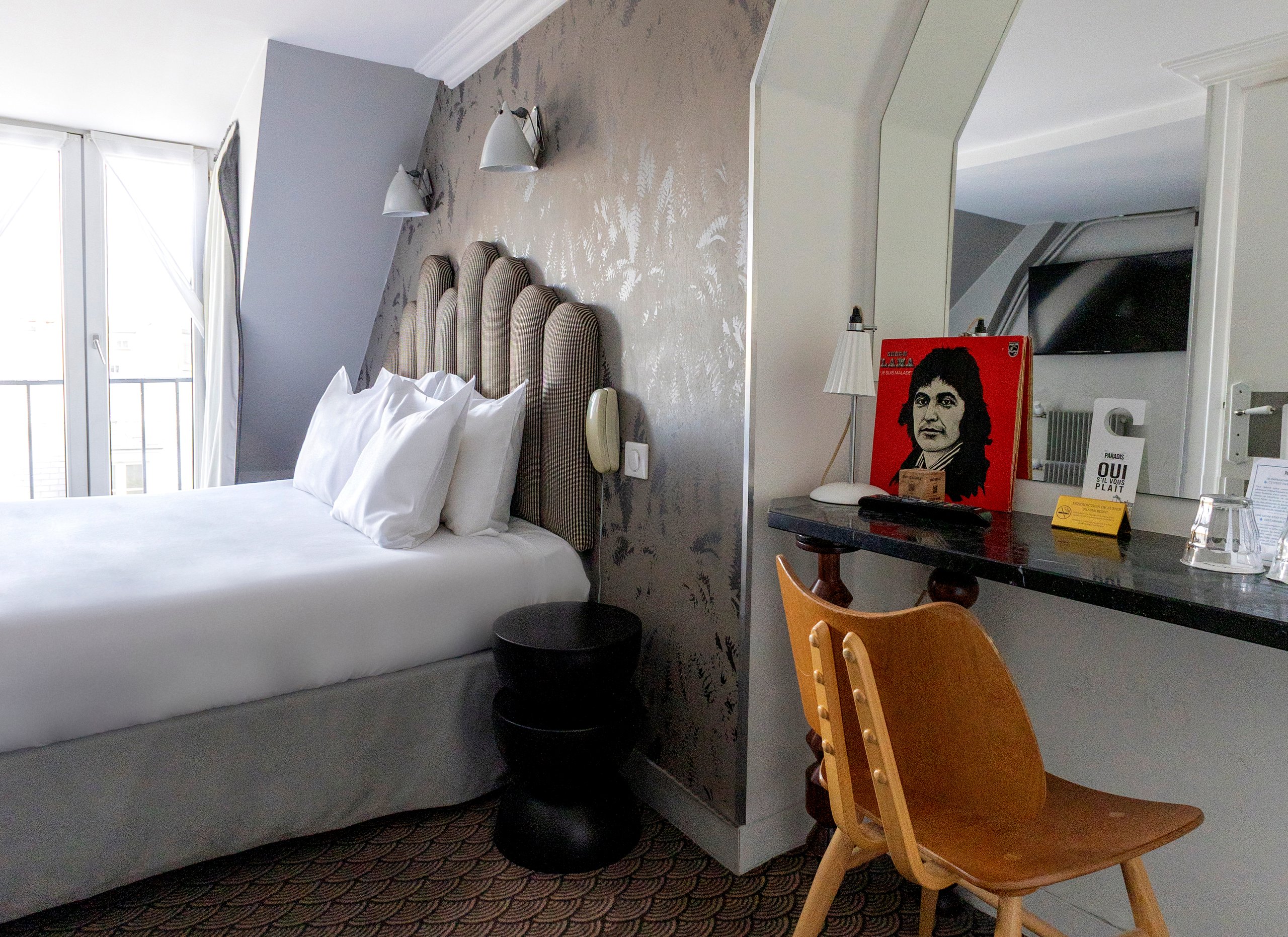 Chambre d'hôtel avec lit blanc, radiateur vintage, bureau et décoration artistique moderne