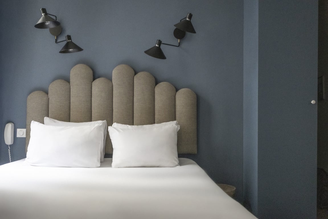 Paradis, Paris: bed with a padded headboard against a grey wall