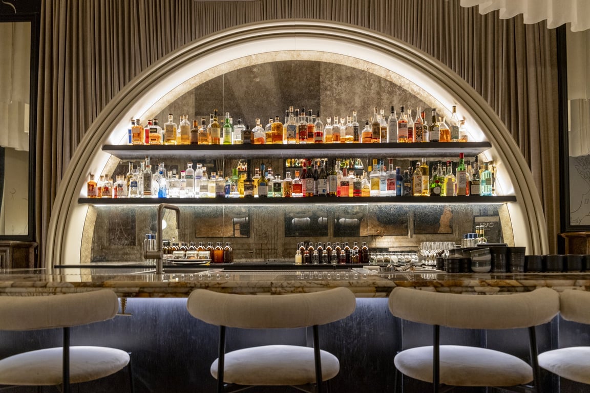 Le bar Casa du Grand Hôtel Français : l’arche de bouteilles rétroéclairée et le comptoir de marbre