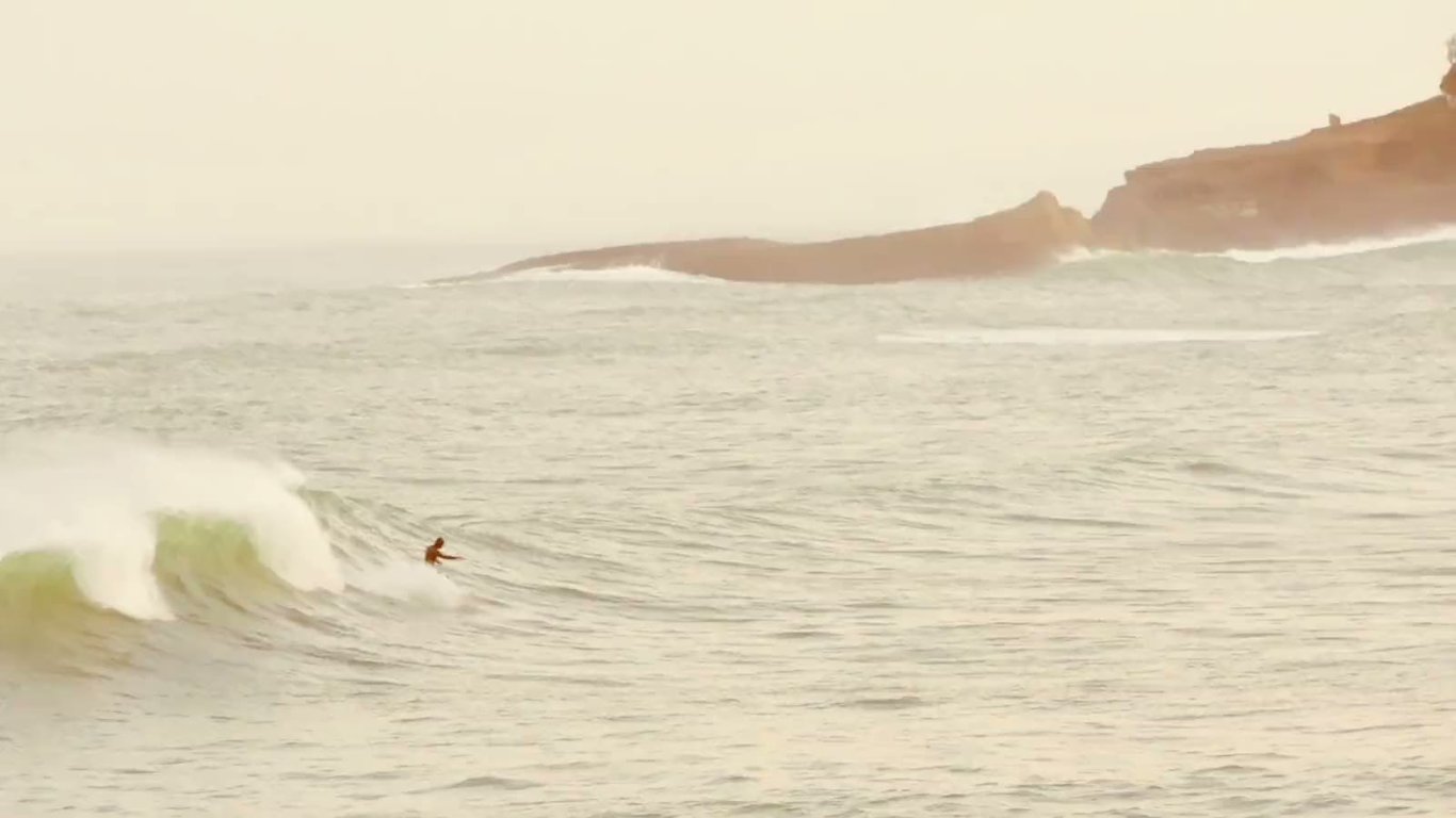 Surfer on a wave off the Basque coast, facing the cliffs